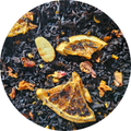 Té negro con trozos de almendra y rodajas secas de naranja en bolsita transparente circular.