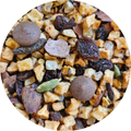 Mezcla de infusión con trozos de manzana, pasas, semillas verdes y pequeñas bolitas marrones, fondo de rooibos.