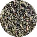 Té azul con hojas secas verdes y marrones, trozos de limón y algas en mezcla artesanal.