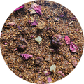 Mezcla de té rooibos con flores secas y piezas pequeñas de fruta papaya visibles.