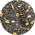 Hojas de té negro con trozos secos de naranja en primer plano.