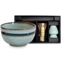 Set para matcha que incluye bowl cerámico azul verdoso, batidor de bambú y cucharilla, presentado en estuche negro.